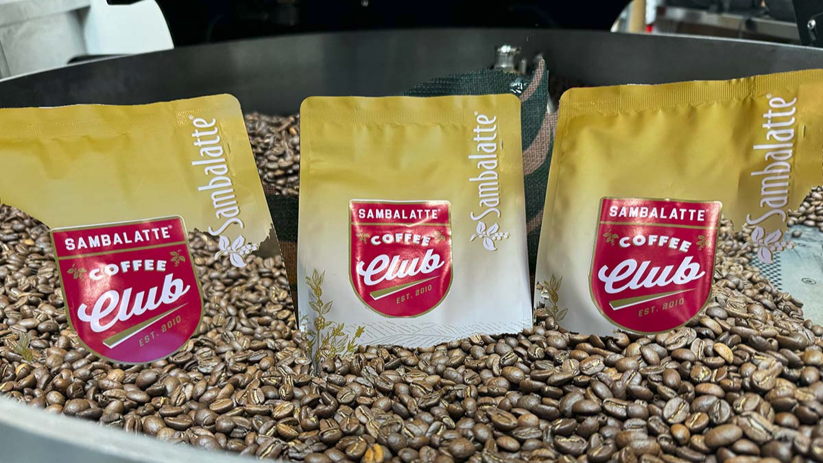 Three Sambalatte Coffee Club packages on a bed of coffee beans.